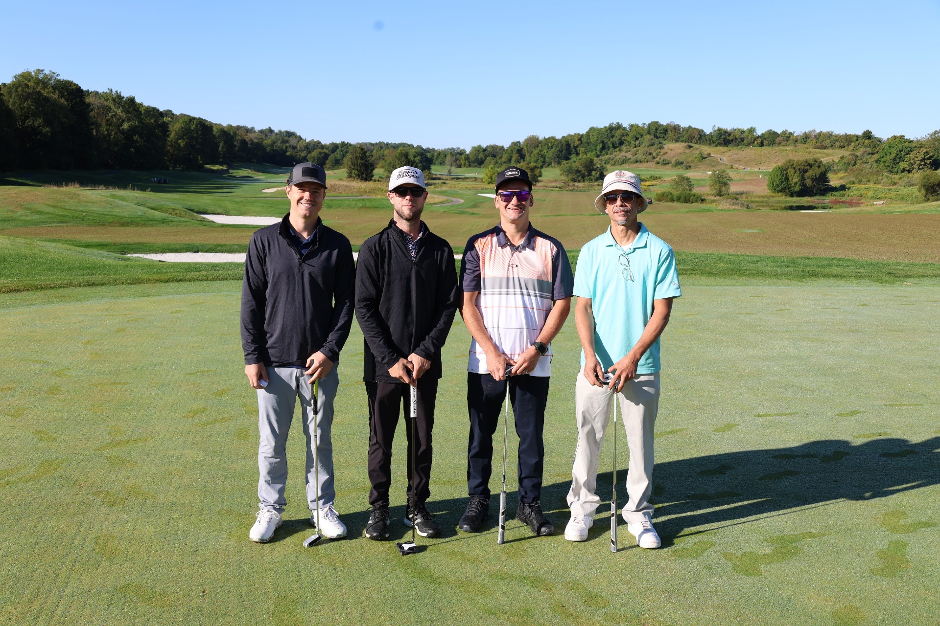 Foursome on the green with rolling fairway behind